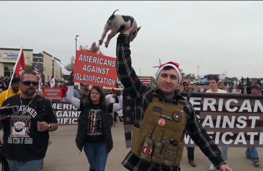 أمريكي يضع نسخة من القرآن الكريم في فم خنزير خلال احتجاج مناهض للإسلام في تكساس بأمريكا